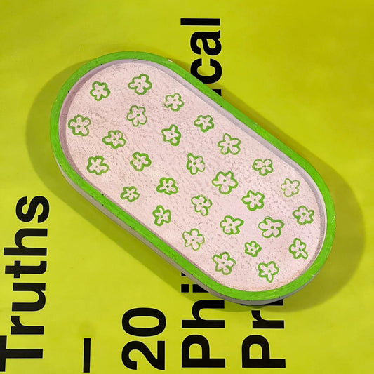 Small pink item with green floral pattern on a yellow background with text