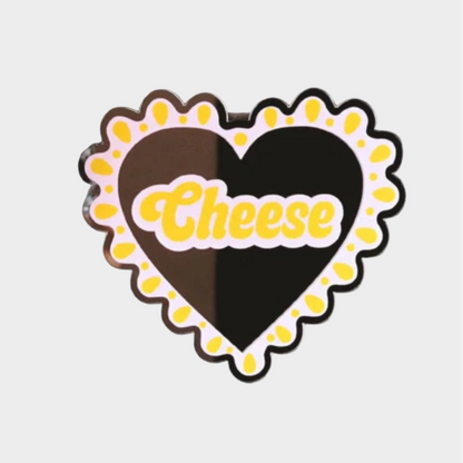 Heart-shaped cheese board with 'Cheese' text on a tiled wall background