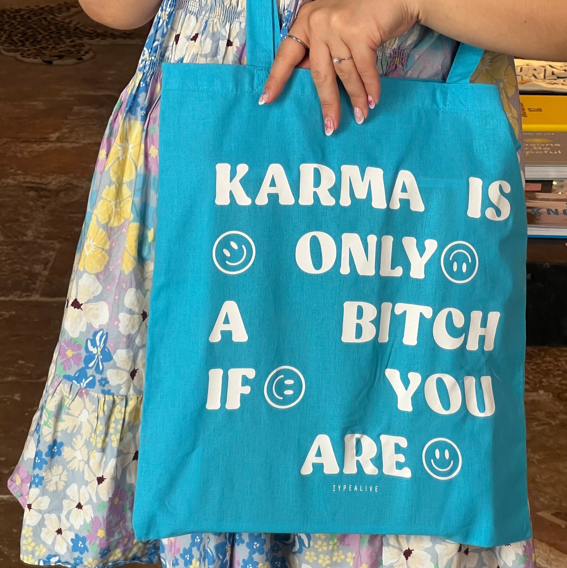 Person holding a blue tote bag with text and smiley faces.