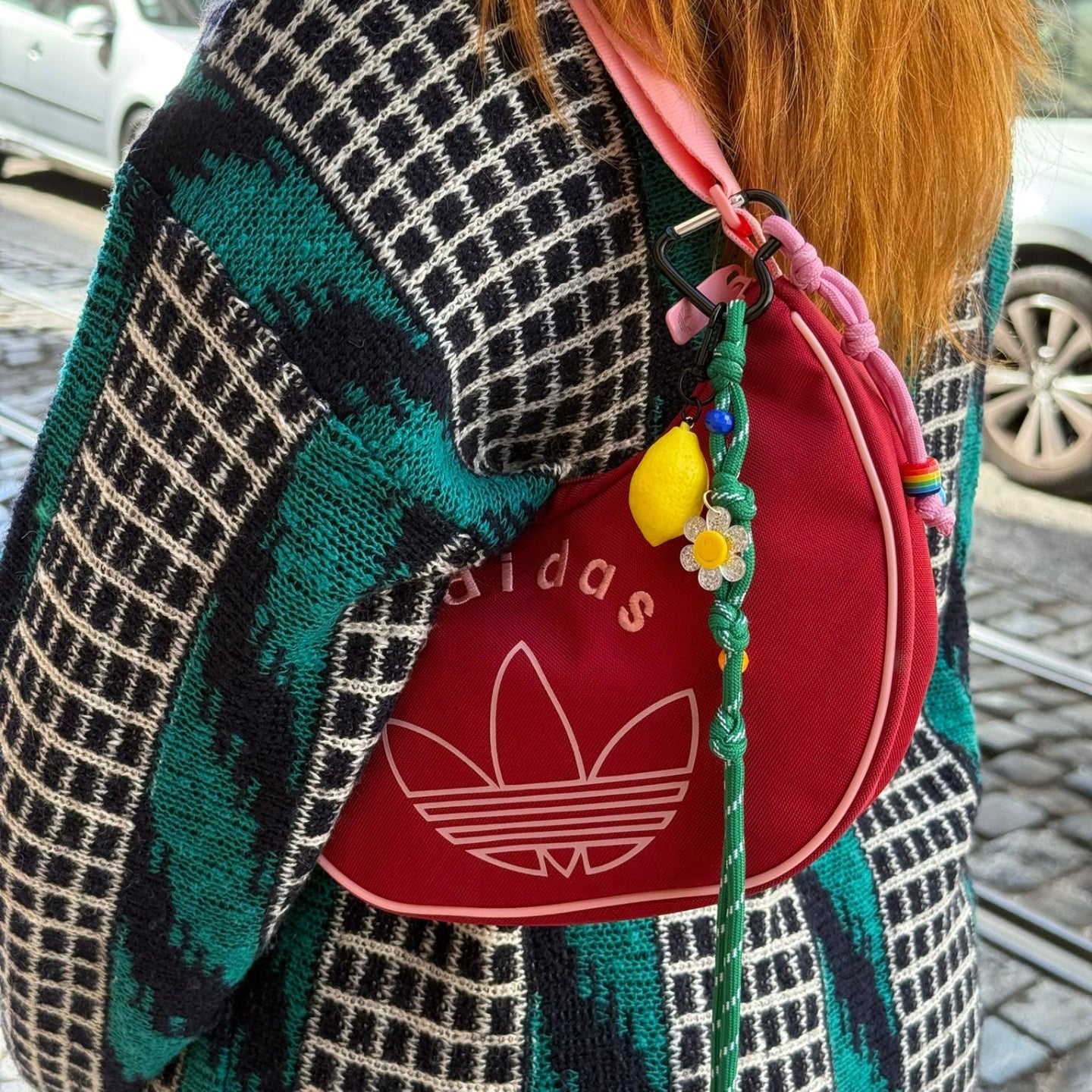 Person wearing a colorful patterned sweater with a red Adidas bag.