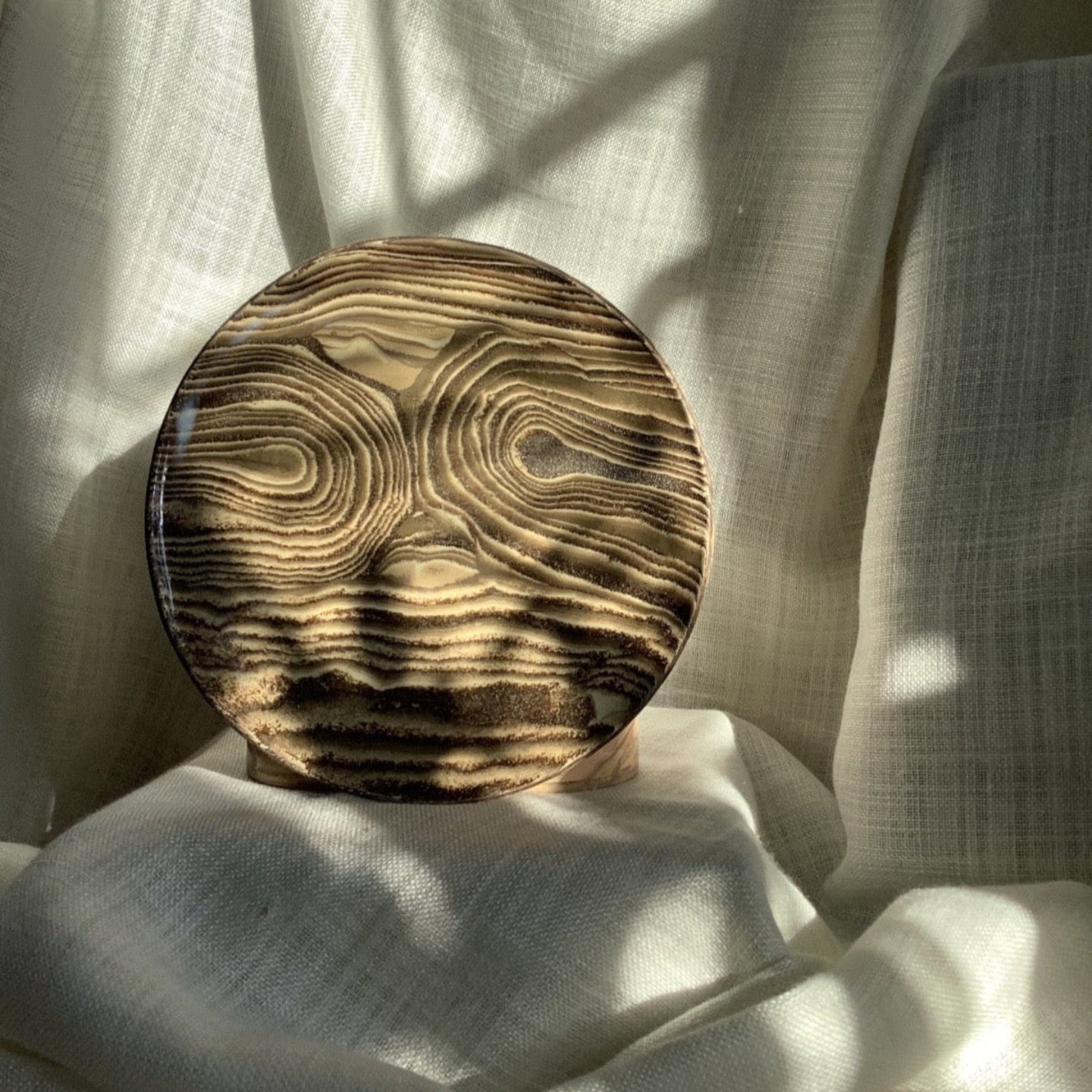Wooden bowl with a textured surface on a white fabric background