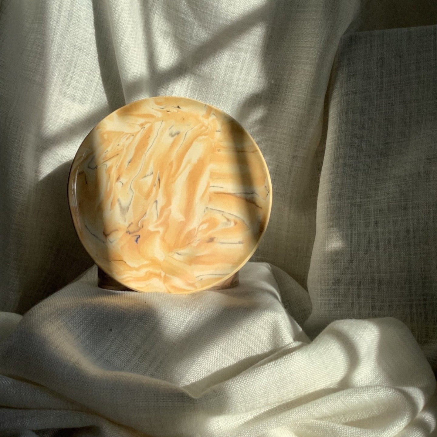 Round marble object on a textured white surface with soft lighting