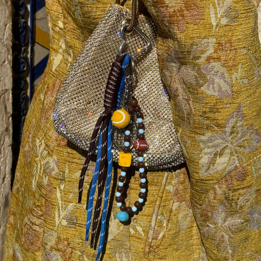 Decorative beaded bag with colorful strings on a textured fabric background