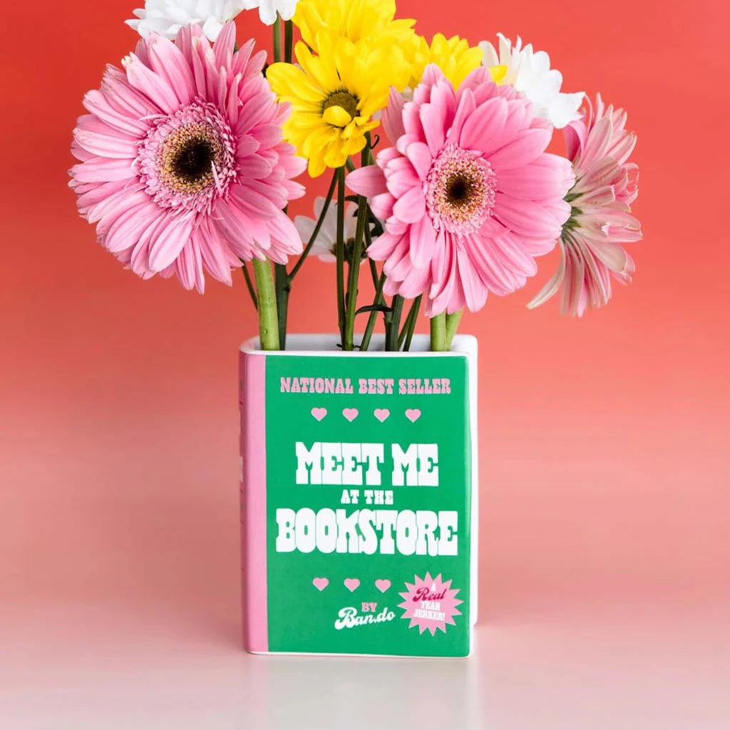 Flowers in a book-shaped container with a pink and green design on a gradient background