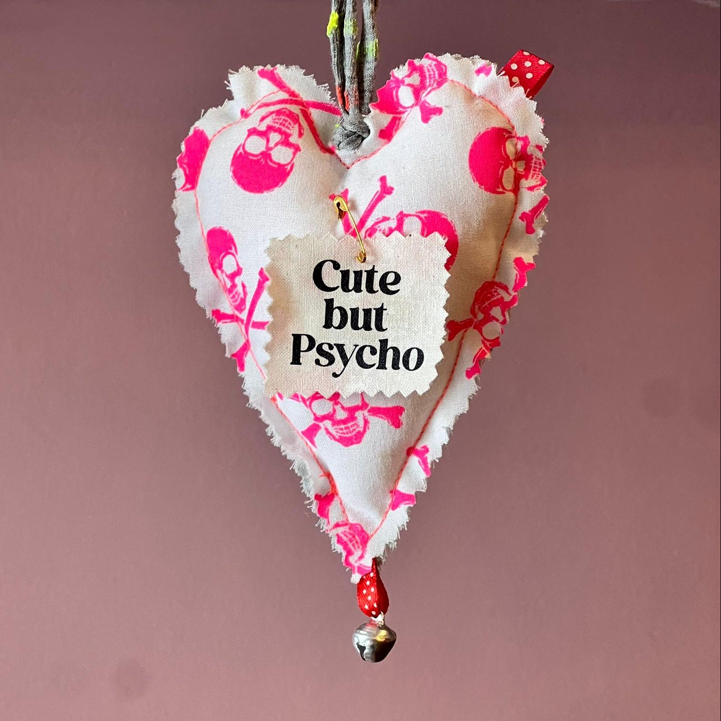 Heart-shaped decorative item with 'Cute but Psycho' text on a pink background