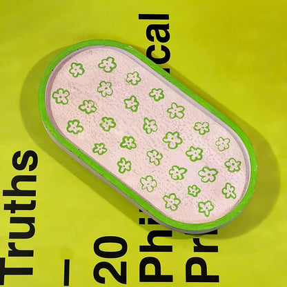 Small pink item with green floral pattern on a yellow background with text