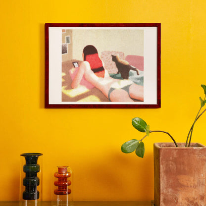 Framed artwork of a woman on a couch against a yellow wall with decorative vases and a plant.