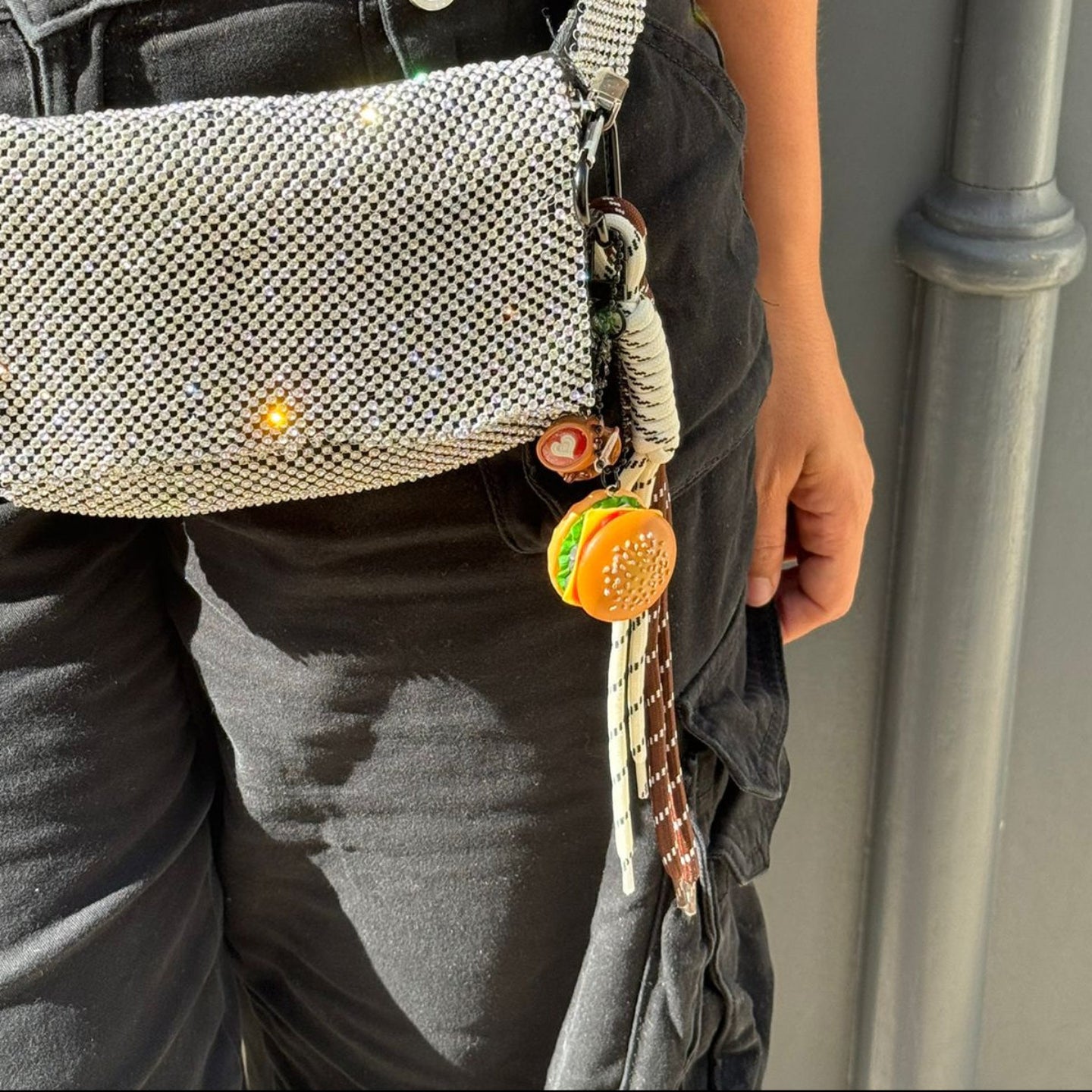 Person wearing a gray waist bag with a keychain on a neutral background