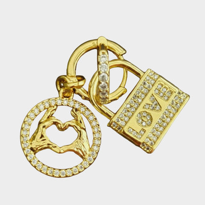 Gold earrings like keychain with lock and heart design on a white background